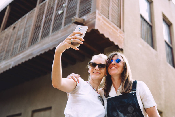 deux jeunes femmes heureuses prenant selfie à la vieille rue à Dubaï, EAU
 - Photo, image
