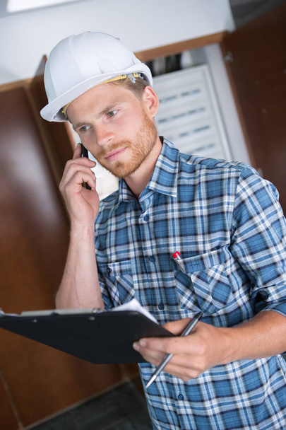 busy construction engineer talking on phone and holding clipboard - 写真・画像