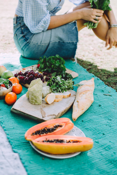 young woman relaxing at summer picnic lying on mat with healthy food  - Photo, Image