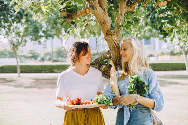 молоді щасливі жінки зі здоровою їжею для літнього пікніка на відкритому повітрі
 - Фото, зображення
