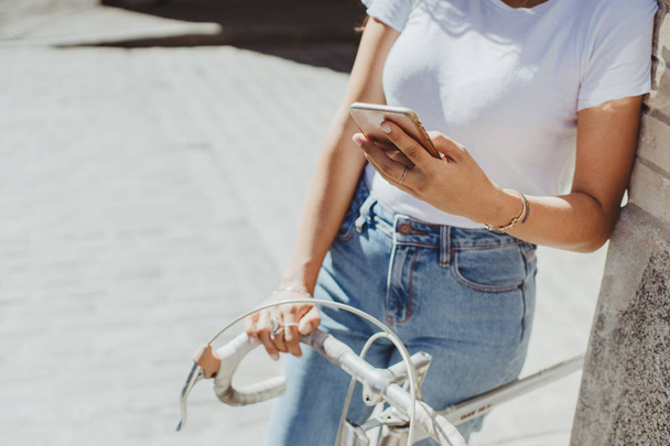 Fechar as mãos femininas verificando novas mensagens no telefone inteligente moderno depois de andar de bicicleta
 - Foto, Imagem