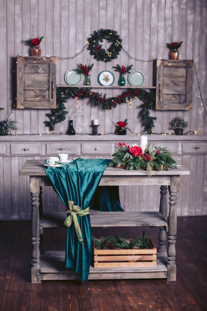 Christmas decor in a wooden house. The shelf is decorated with a garland and fir branches. Wooden table with decor - Foto, imagen