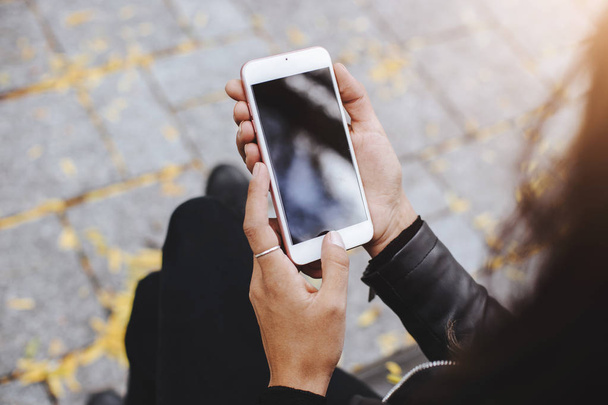 Κοροϊδεύω εικόνα Γυναικεία χέρια κρατώντας το λευκό κινητό τηλέφωνο με κενή οθόνη εξωτερική - Φωτογραφία, εικόνα