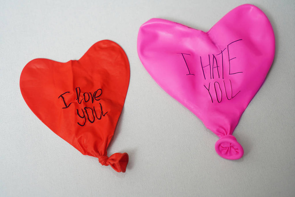pari deflatoituja ilmapalloja sanoilla: vihaan sinua ja rakastan sinua paperilla tekstuuri tausta. kaksi kumipalloa
 - Valokuva, kuva