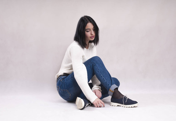 triste chica se sienta en el suelo en jeans
 - Foto, Imagen