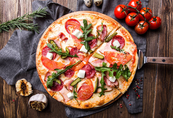 Tasty Italian pizza on a dark wooden background top view - Фото, изображение