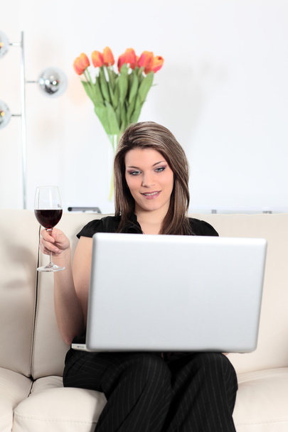 On sofa with computer and wine glass - 写真・画像