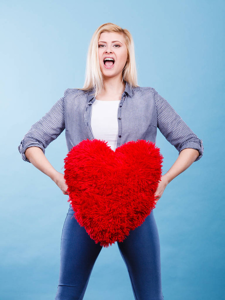 Happy woman holding red pillow in heart shape - 写真・画像