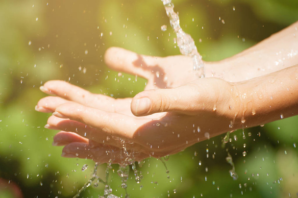 Donna che lava le mani all'aperto. Acqua potabile naturale nel palmo della mano
. - Foto, immagini