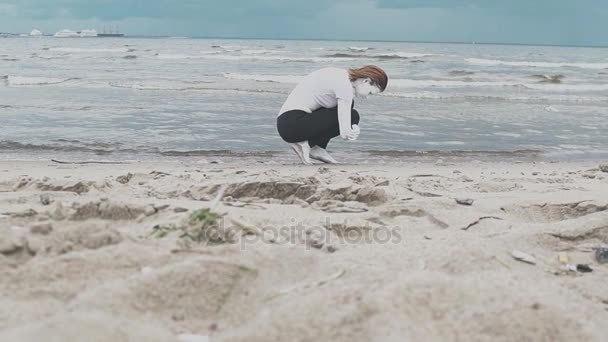 Sanatsal kız beyaz boya kaplı kumlu deniz sahilinde çömelmiş - Video, Çekim
