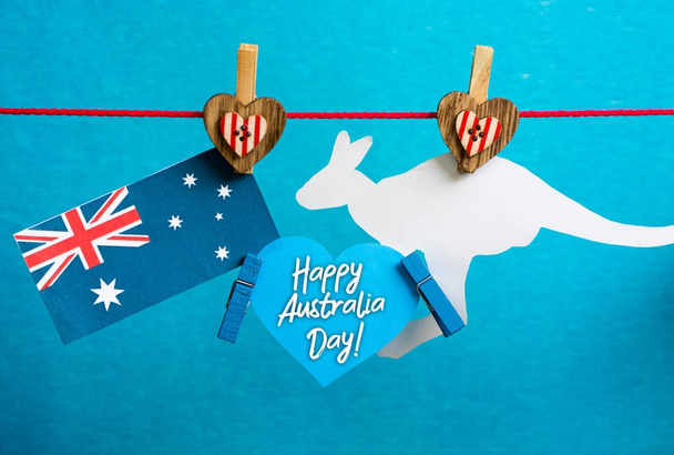 Celebre o feriado do Dia da Austrália em 26 de janeiro com um cartão escrito de saudação de mensagem do Dia da Austrália feliz através de mapas australianos e pinos suspensos de bandeira no fundo azul
.  - Foto, Imagem