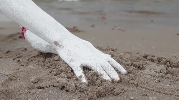Művészi lány borított fehér festékkel ága megragadja a nedves homok, a tenger partján - Felvétel, videó