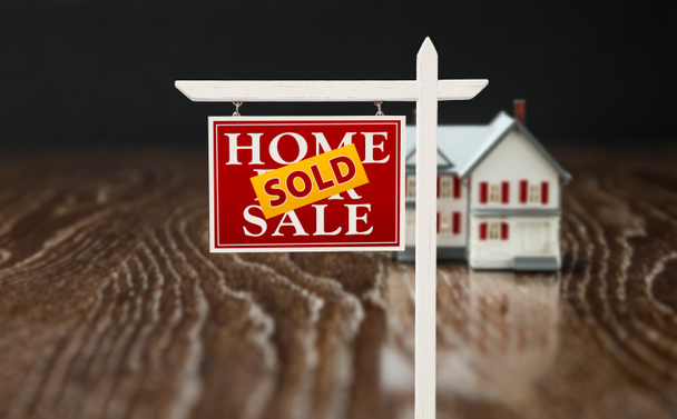 Sold For Sale Real Estate Sign In Front of Model Home on Reflective Wooden Surface. - Photo, Image