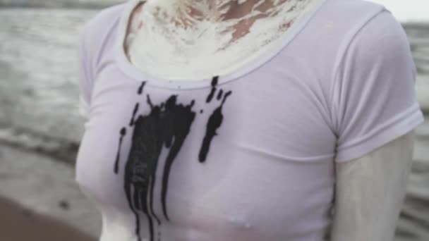 Zwarte spit merken op activist kunstenaar vrouwelijke shirt op zee - Video