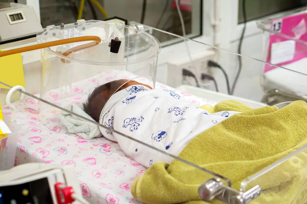 Nemocné novorozence s respiračními problémy pouze spí na dětské postýlky a opotřebení pole kyslíku pro pomáhá snadněji dýchat a vyléčit z dýchacích cest v nemocnici. - Fotografie, Obrázek