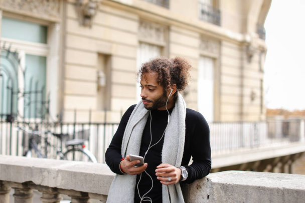 Mulatto male person chatting with friends by smartphone with ear - Foto, Imagen