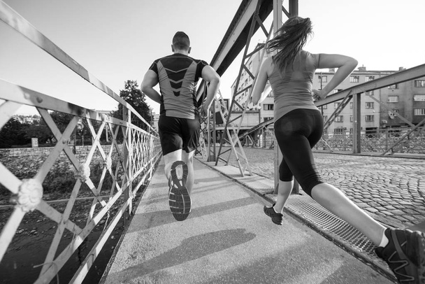 stedelijke sport, gezonde jonge paar joggen over de brug in de stad op zonnige ochtend - Foto, afbeelding