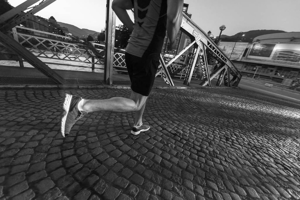 urban sports, young healthy man jogging across the bridge in the city at early morning - Fotoğraf, Görsel