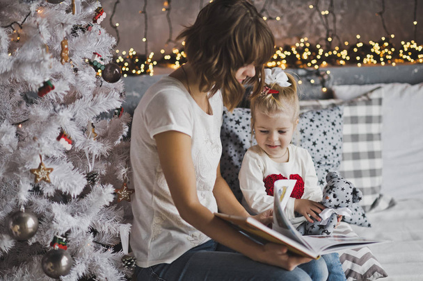 Mère fille ans lire le livre dans les décorations de Noël
  - Photo, image