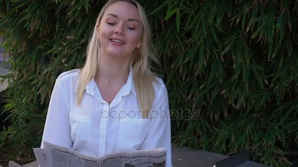 Lady reading newspaper outdoors in slow motion with close up face. - Záběry, video