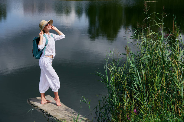 Νεαρή γυναίκα που αναπαύεται κοντά στη λίμνη - Φωτογραφία, εικόνα