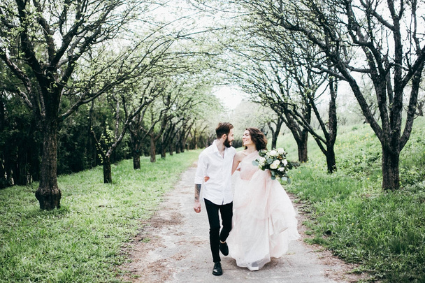 Newlyweds embracing while walking by spring yard - Foto, Imagen