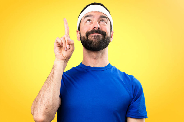 Funny sportsman pointing up on colorful background - Photo, Image