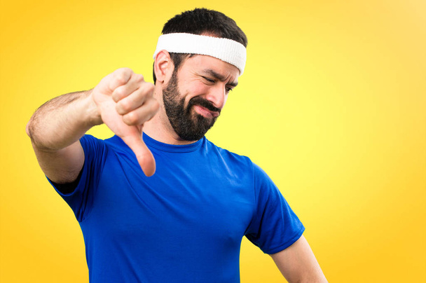 Funny sportsman making bad signal on colorful background - Photo, Image
