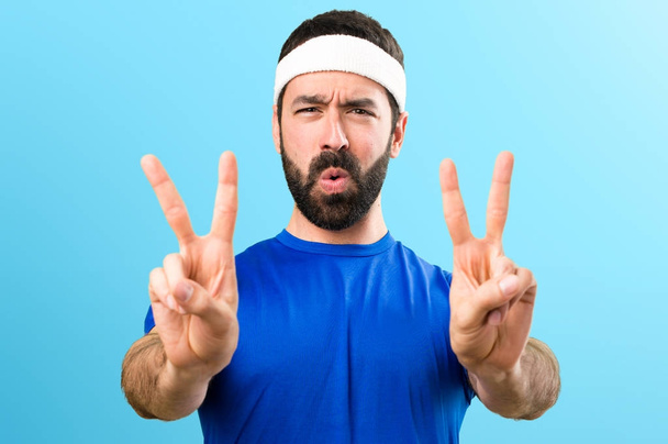 Funny sportsman making victory gesture on colorful background - Foto, immagini