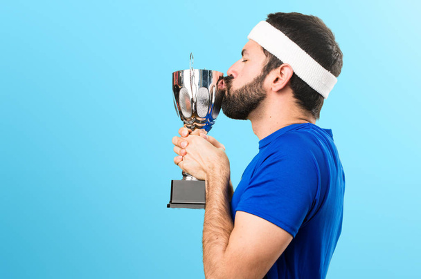 Funny sportsman holding a trophy on colorful background - Zdjęcie, obraz