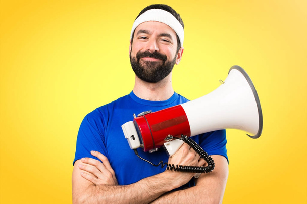 Happy Funny sportsman holding a megaphone on colorful background - Foto, Imagem