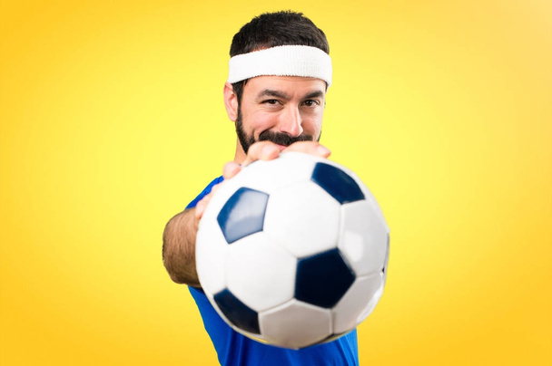 lustiger Sportler, der einen Fußball auf buntem Hintergrund hält - Foto, Bild