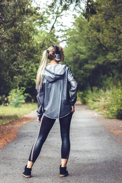 красивая молодая девушка гуляет по парку, слушая музыку на ч
 - Фото, изображение