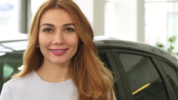 Χαρούμενα ελκυστική γυναίκα, που χαμογελά δείχνει τα κλειδιά του αυτοκινήτου στη φωτογραφική μηχανή στην αντιπροσωπεία - Πλάνα, βίντεο