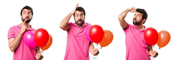 Aantal knappe jonge man houden ballonnen en twijfels - Foto, afbeelding