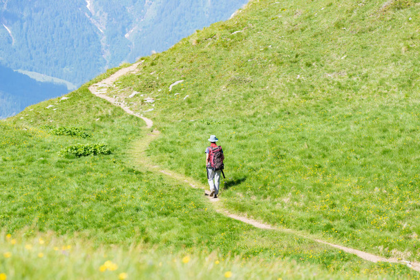 Backpacker walking on hiking trail in the mountain. Summer adventures summer vacation on the Alps. Wanderlust people traveling concept. - Photo, Image