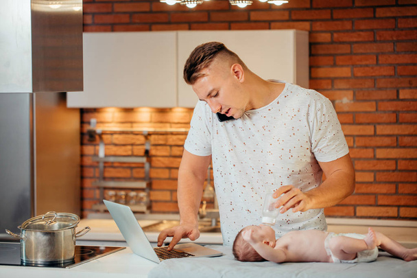Father Feeding His Baby While trying Working on laptop - Photo, image