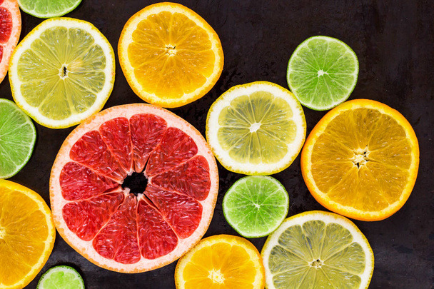 top view of slices of citrus fruits on black background - Photo, Image