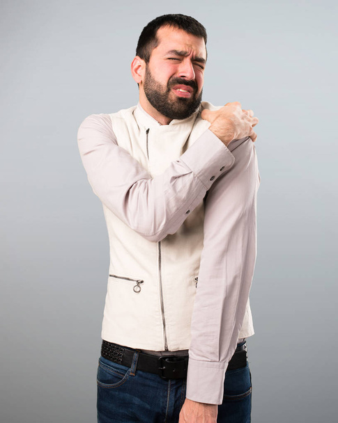 Hombre guapo con chaleco con dolor de hombro sobre fondo gris
 - Foto, Imagen