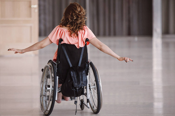 Mulher deficiente feliz em uma cadeira de rodas de volta
 - Foto, Imagem