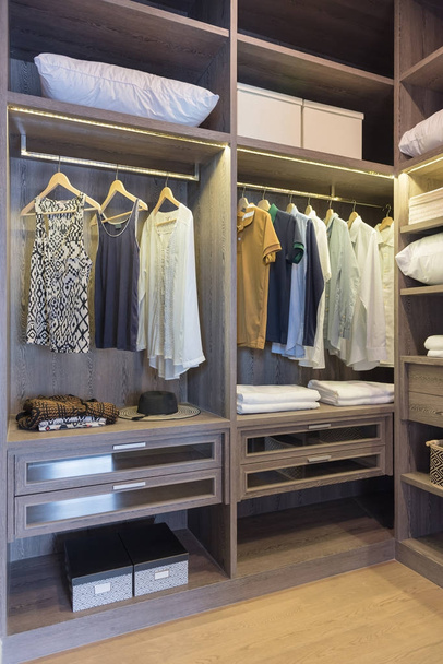 armario de madera en walk in closet con ropa colgando en el carril, concepto de diseño de interiores
 - Foto, imagen