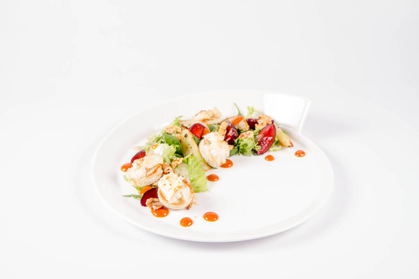 Starter: Mix salads, baked goat cheese, sea-buckthorn jam, caramelized pear with thyme, plum and roast nuts - on a white background - Фото, изображение