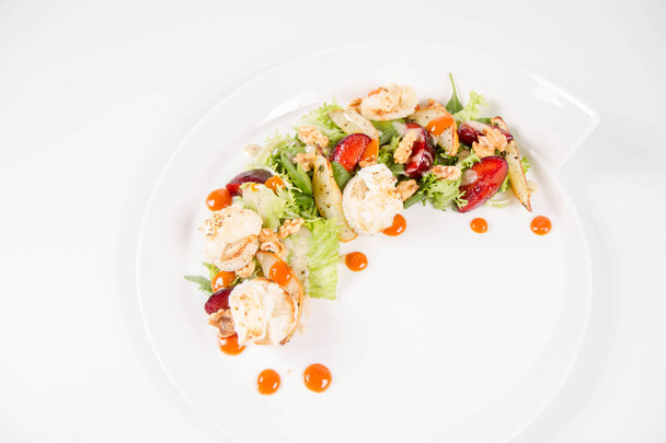 Voorgerecht: Meng salades, zee-duindoorn jam, gebakken geitenkaas en gekarameliseerde peren met tijm, pruim en geroosterde noten - op een witte achtergrond - Foto, afbeelding