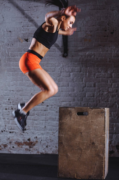 woman box jumping at cross fit gym. athlete doing box jumps exercise at gym - Zdjęcie, obraz