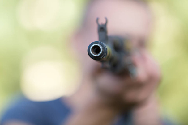 Man with Kalashnikov rifle took aim outdoors - 写真・画像