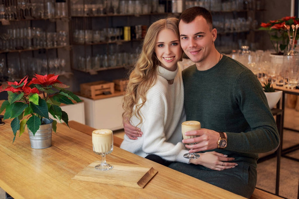 Ein Paar ist auf einem Date. Sie umarmen sich und lächeln. Junge Leute trinken Kaffee. Valentinstag. - Foto, Bild