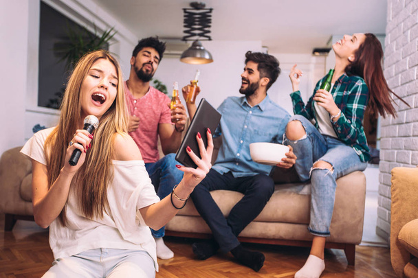 Grupa przyjaciół grająca w karaoke w domu. Koncepcja przyjaźni, rozrywki domowej i ludzi - Zdjęcie, obraz