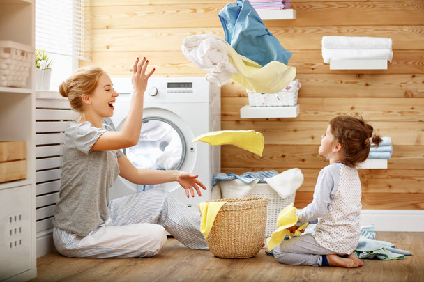 Família feliz mãe dona de casa e filho na lavanderia com lavatório
 - Foto, Imagem
