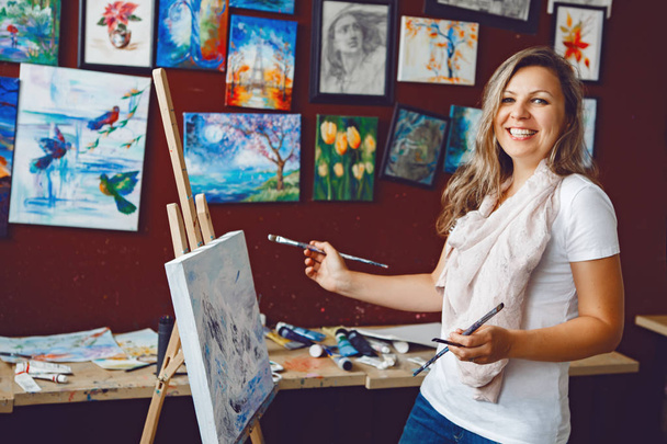 Muotokuva nuori kaunis keski-ikä valkoinen valkoihoinen nainen taiteilija piirustus maalaus taidestudiossa akryylimaaleja kankaalle. Elämäntapa harrastus käsite
 - Valokuva, kuva