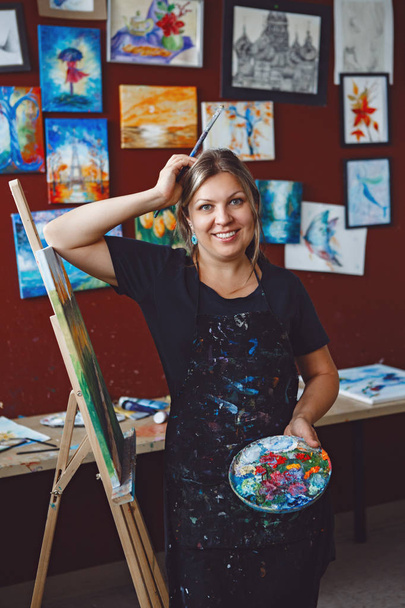 Portré fiatal gyönyörű középkorú fehér-kaukázusi nő művész rajz-festészet-művészeti stúdió, akril festékek, vászon. Életmód tevékenység hobby koncepció - Fotó, kép